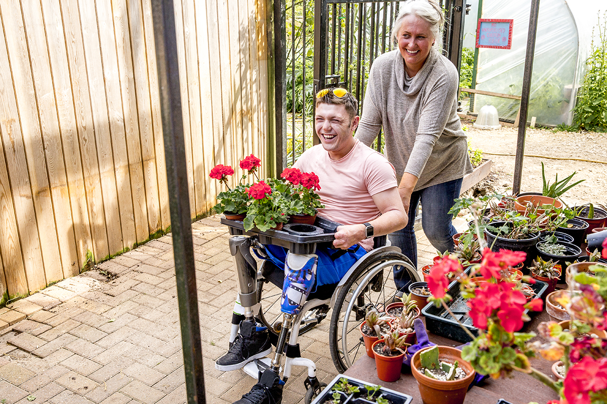 Young man in a wheelchair working in an allotment potting shed