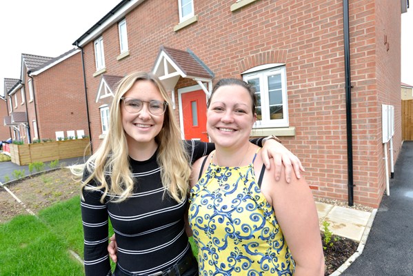 Two ladies smiling outside their new home