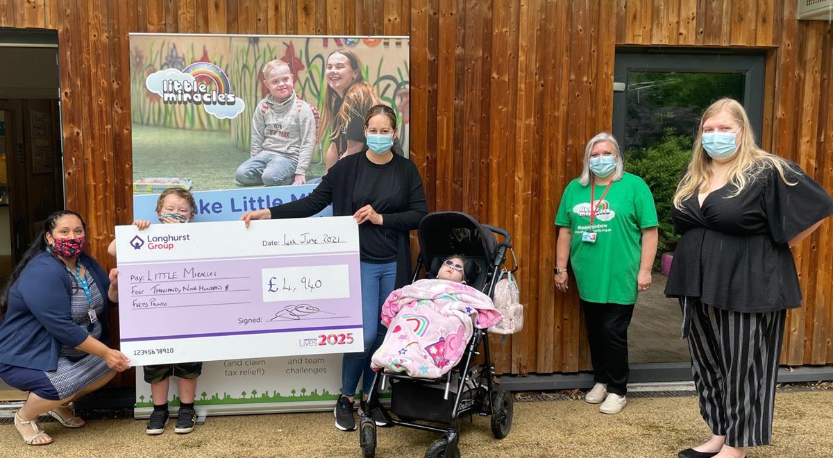 A group of adults and children holding a cheque for "Little Miracles"