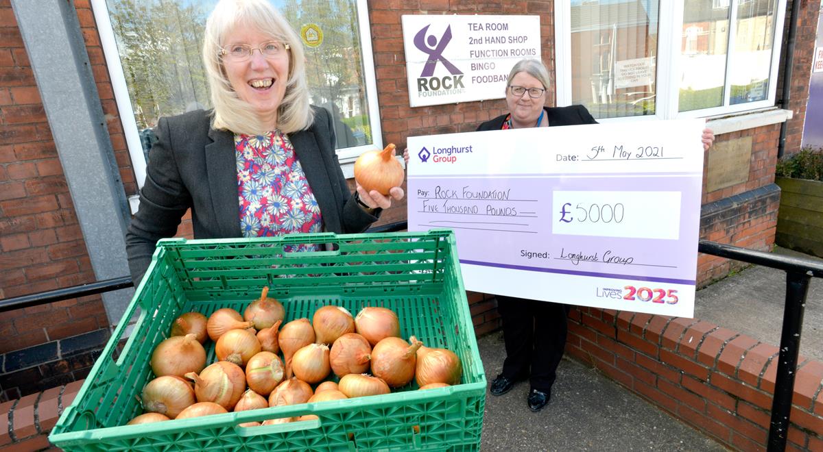One lady holding a cheque, another lady holding a basket of onions