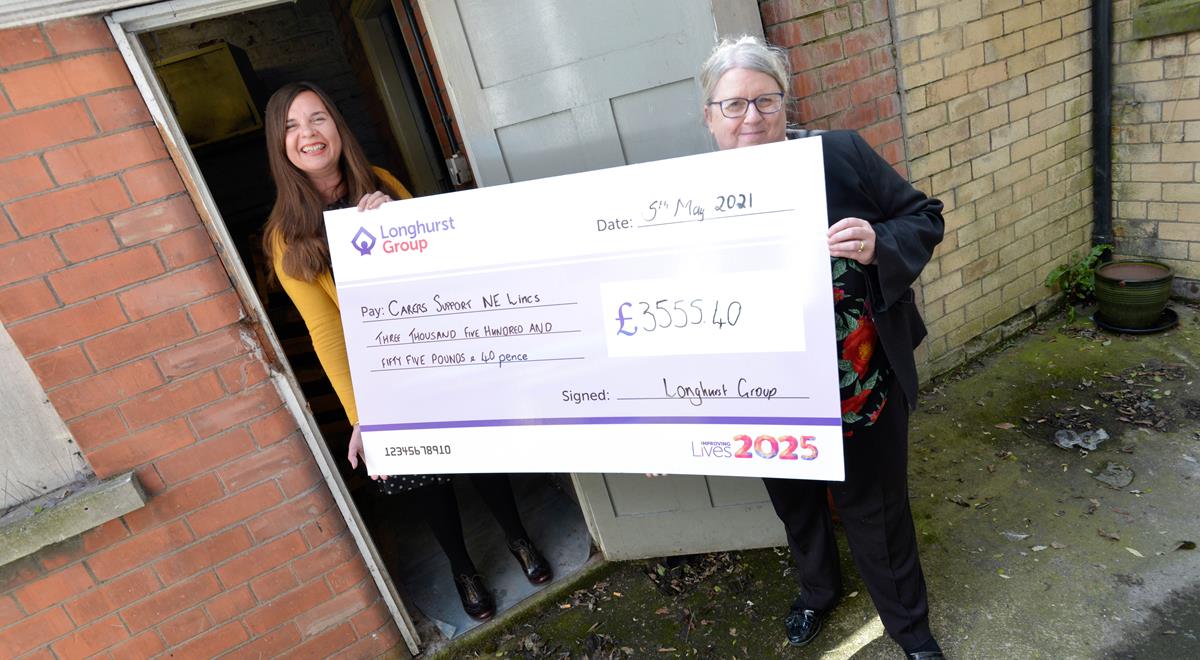 Two ladies holding a cheque for carers support NE Lincs