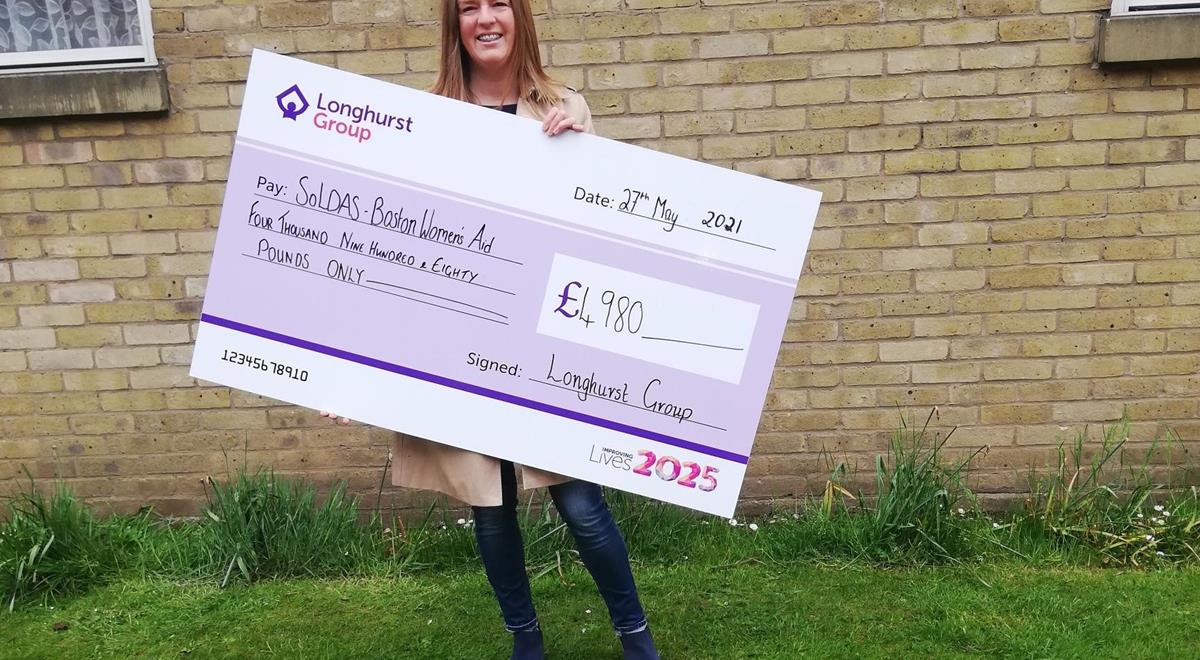 Lady holding a cheque for Boston Women's Aid