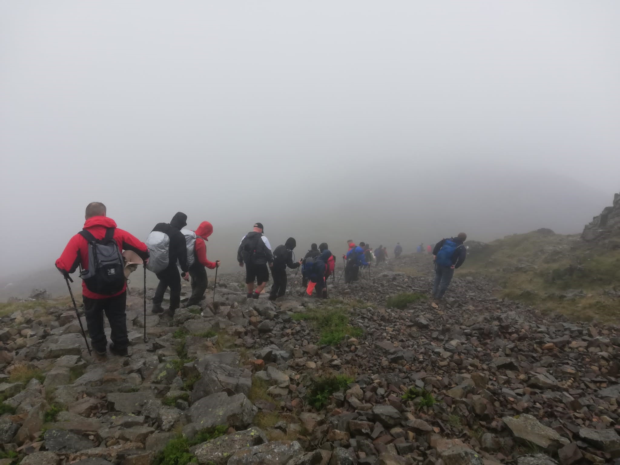 People walking a mountain with low clouds around them