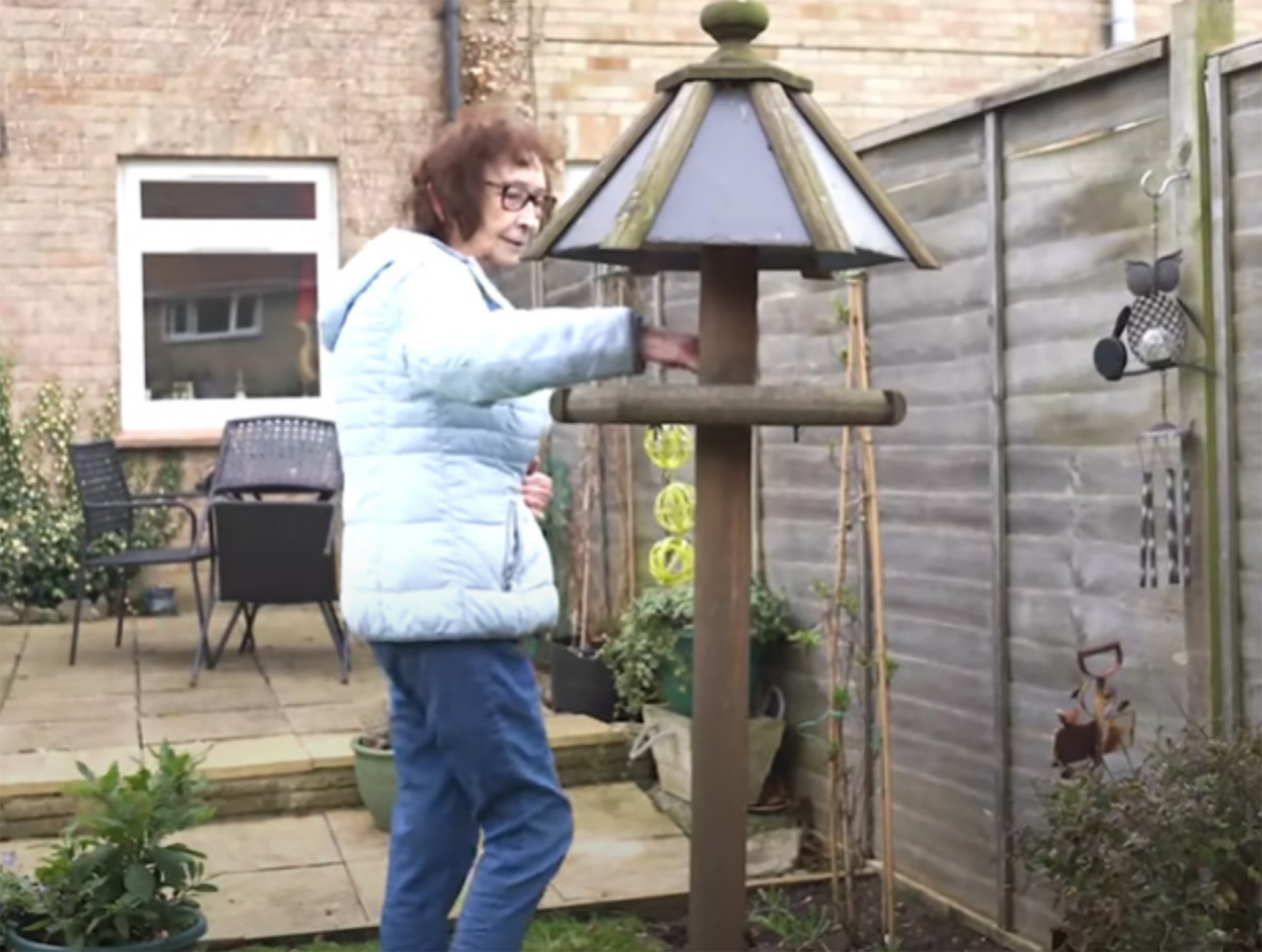 Lady standing near her bird house