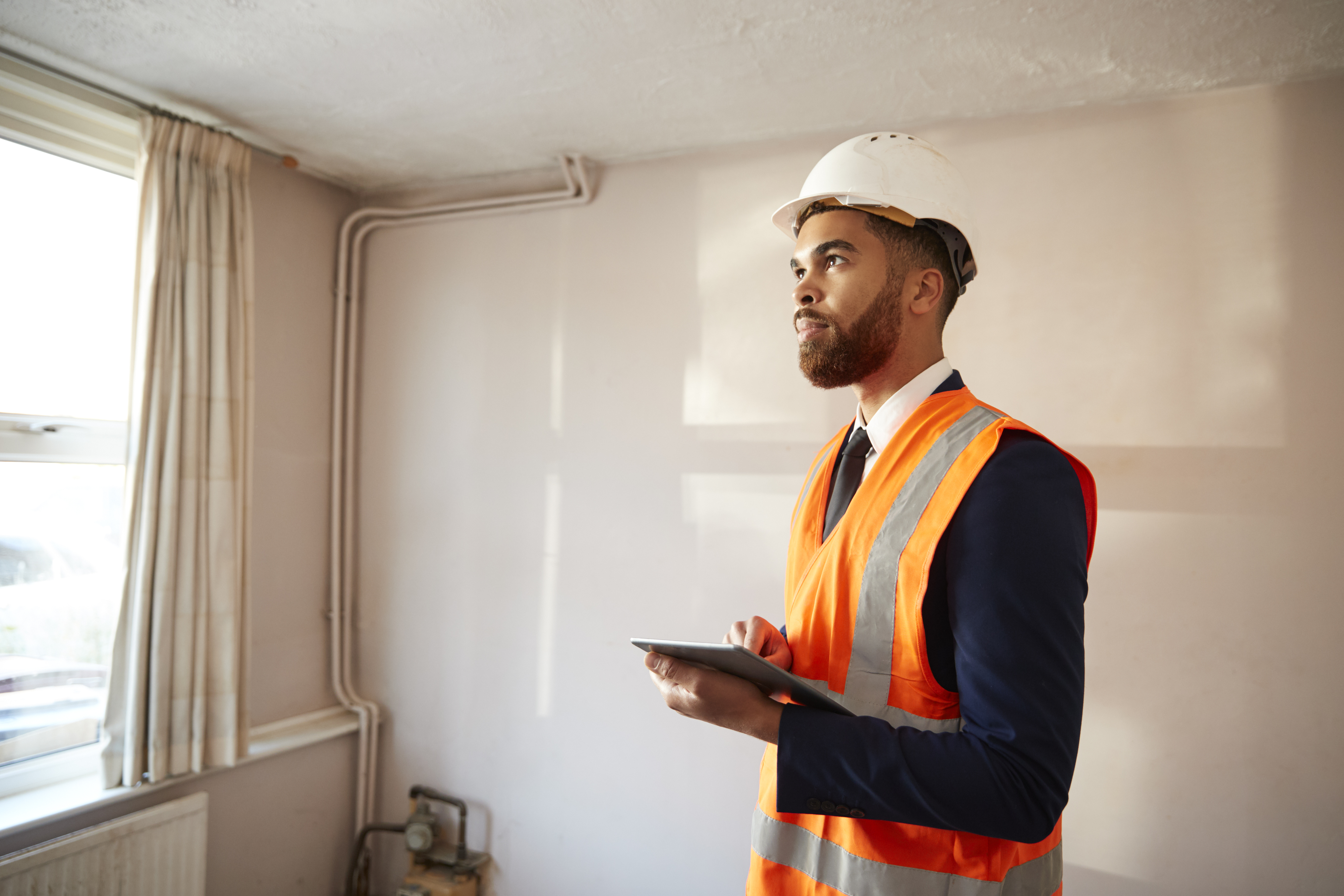 Man in hard hat looking around a room