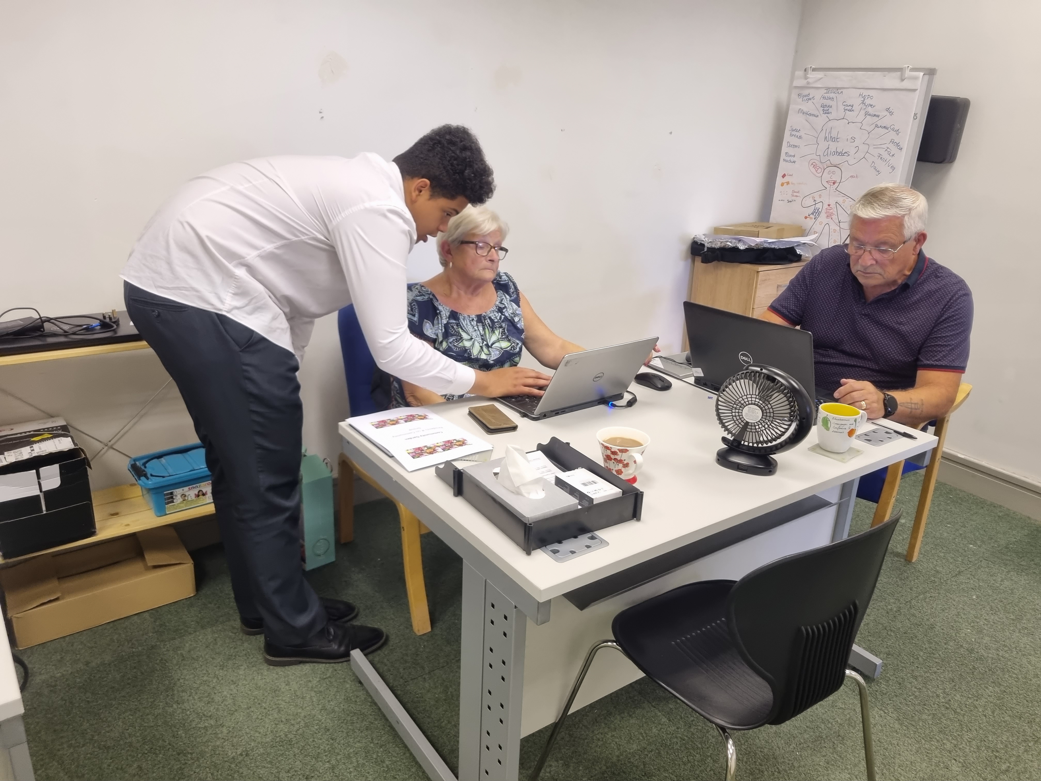 Teenager teaching adults how to use a laptop