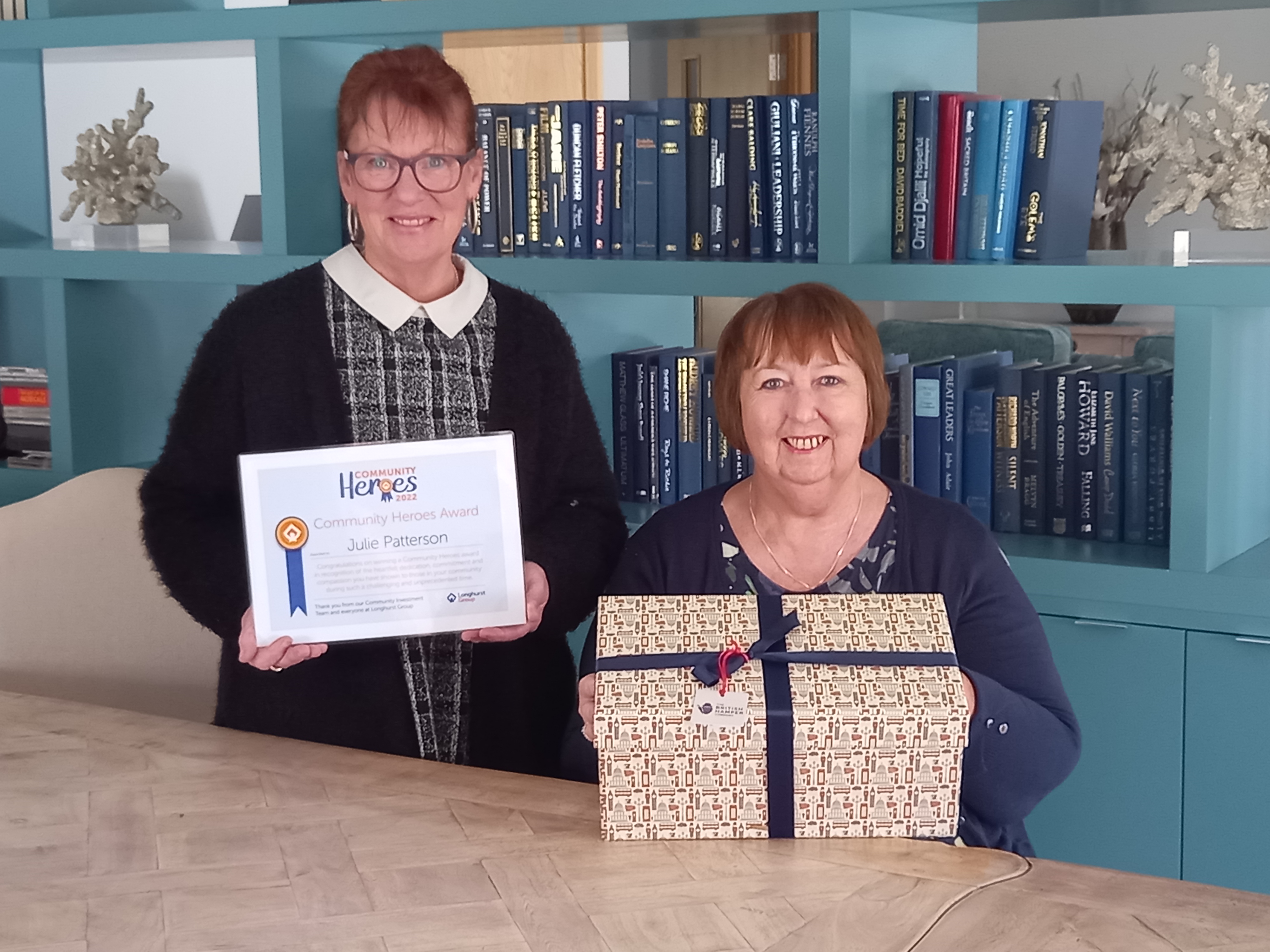 Two ladies standing in front of a bookshelf smiling