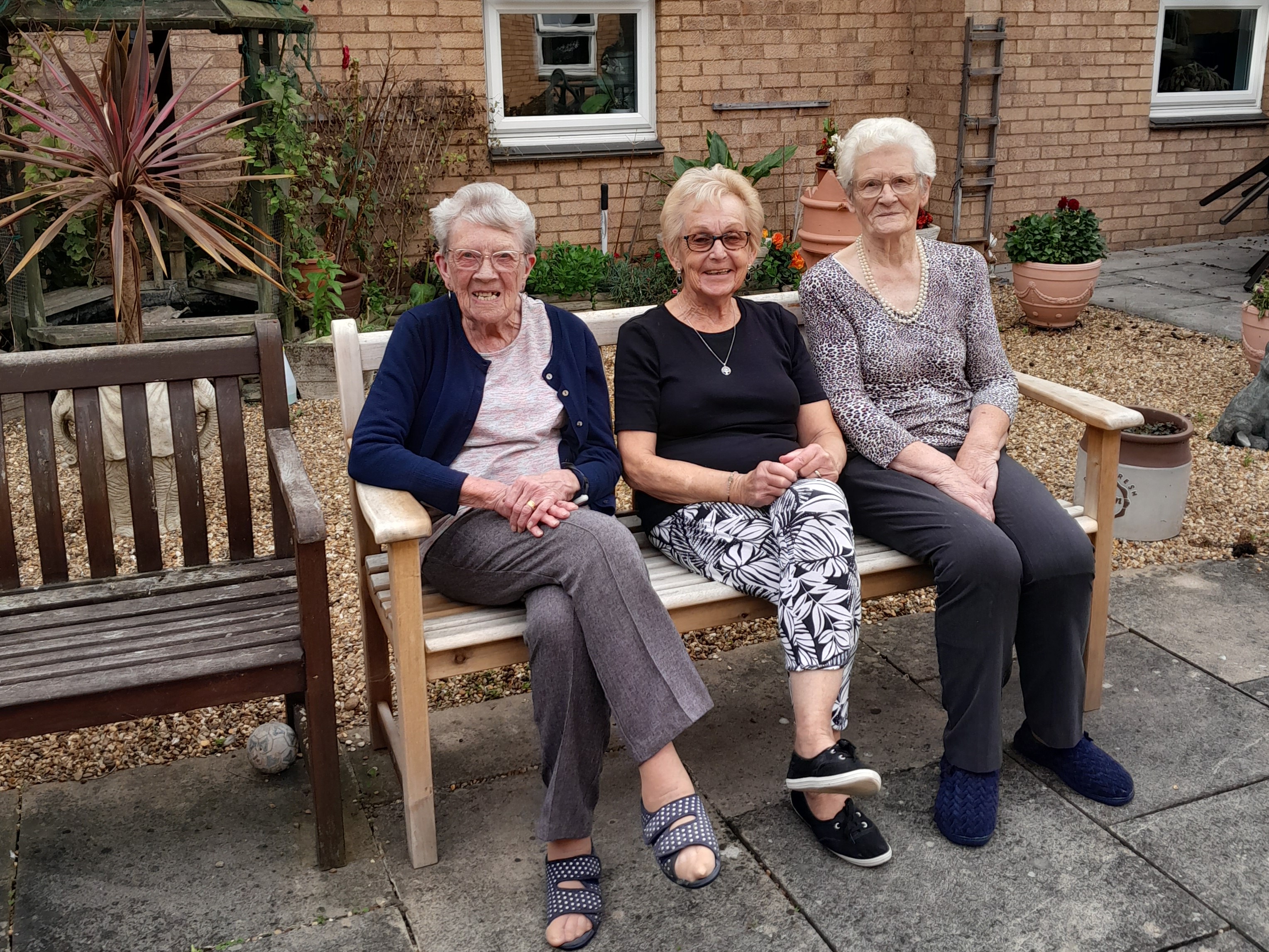 Three ladies sitting on a bench smiling