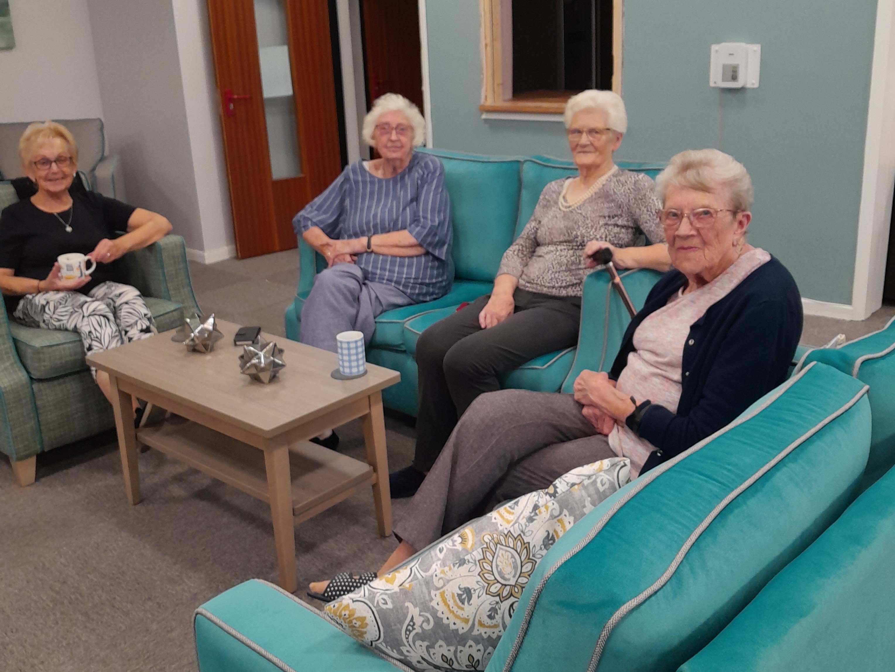 Four ladies sat around a table smiling