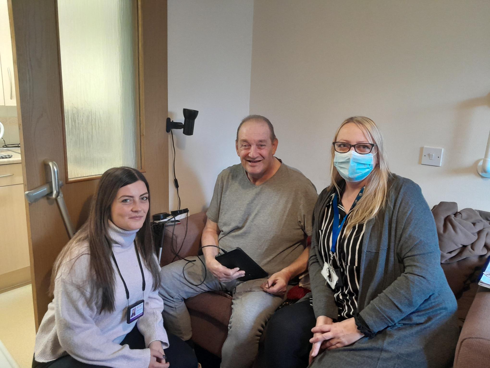 Two women and a man smiling with a new tablet