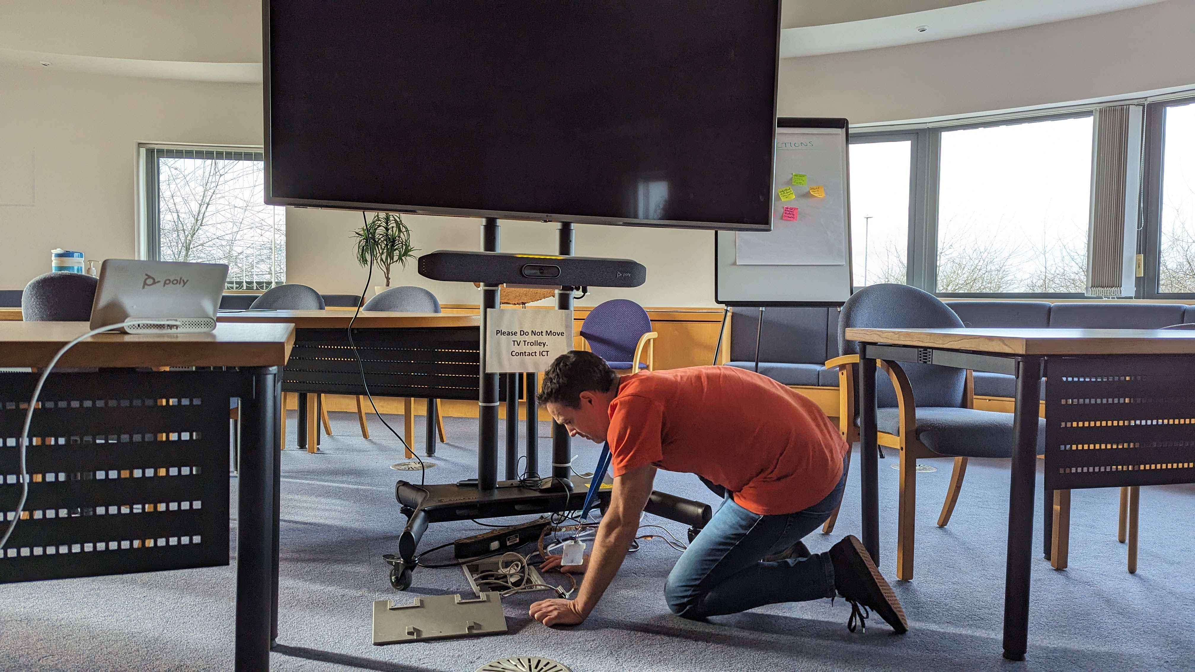 ICT technician kneels to fix some underfloor cables